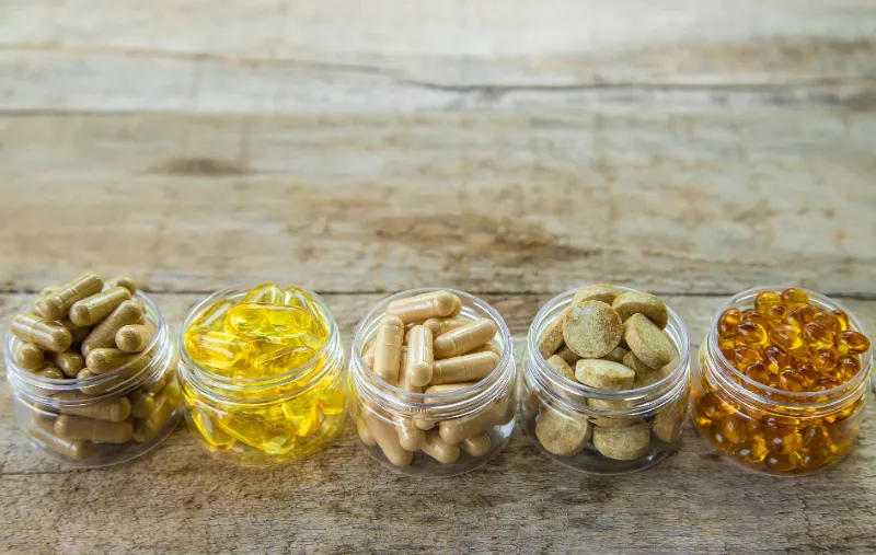 supplements-vitamins-medicinal-herbs-glass-jars-wooden-table
